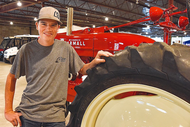 Cole Wolken poses at the 1952 McCormick Farmall he and his dad Troy recently restored. (Julie Smith/News Tribune photo)