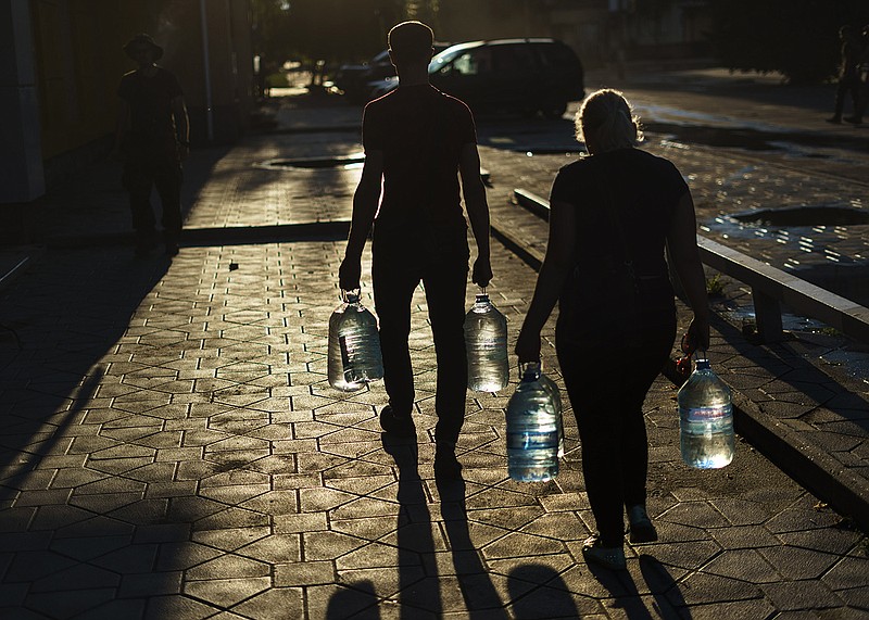 Ukrainians carry bottles of water after filling them in a store Thursday in Pokrovsk in eastern Ukraine.
(AP/David Goldman)