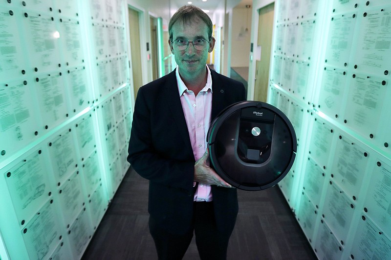 iRobot co-founder and Chief Executive Officer Colin Angle holds a Roomba vacuum in a hallway decorated in patents the company owns, at iRobot headquarters in Bedford, Mass., in this file photo.
(AP)