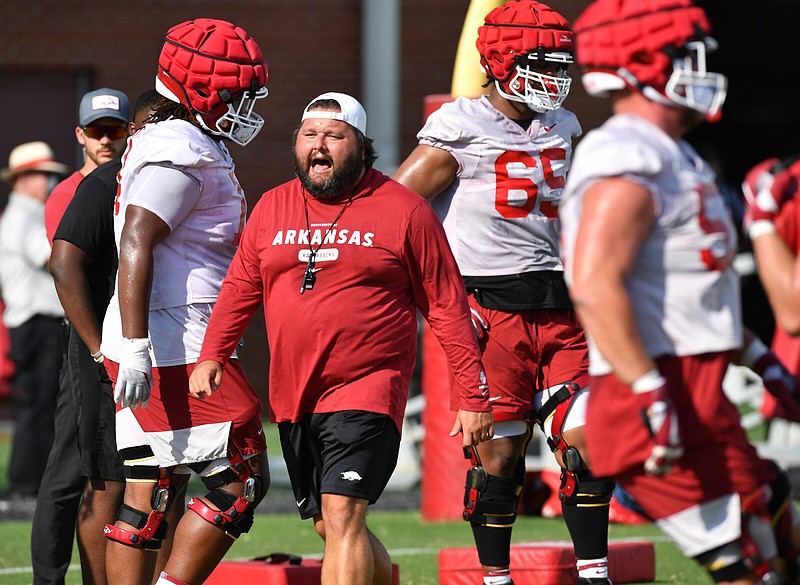 Arkansas offensive line coach Cody Kennedy gives instructions to players during workouts Friday at the Razorbacks’ practice facility in Fayetteville. The Hogs opened preseason drills Friday. More photos available at arkansasonline.com/86uapractice/.
(NWA Democrat-Gazette/Andy Shupe)