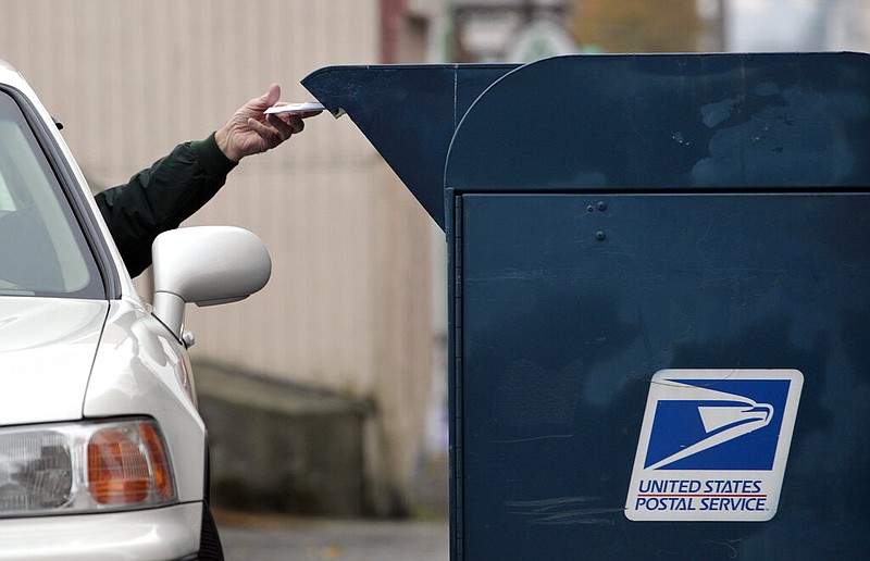 A customer drops mail into a curbside mailbox at a post office in this undated file photo. (AP/Elaine Thompson)