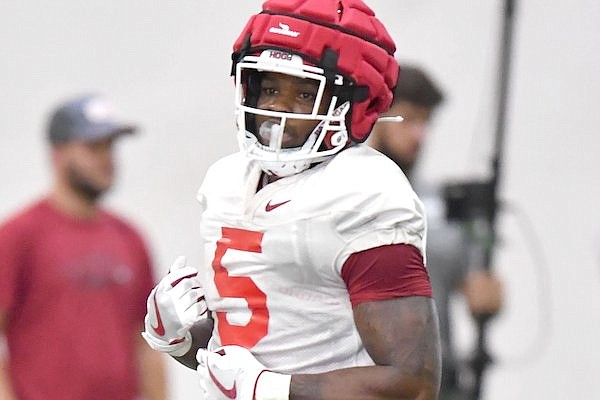 Arkansas running back Raheim Sanders (left) carries the ball Friday, Aug. 5, 2022, during practice at in Fayetteville.
