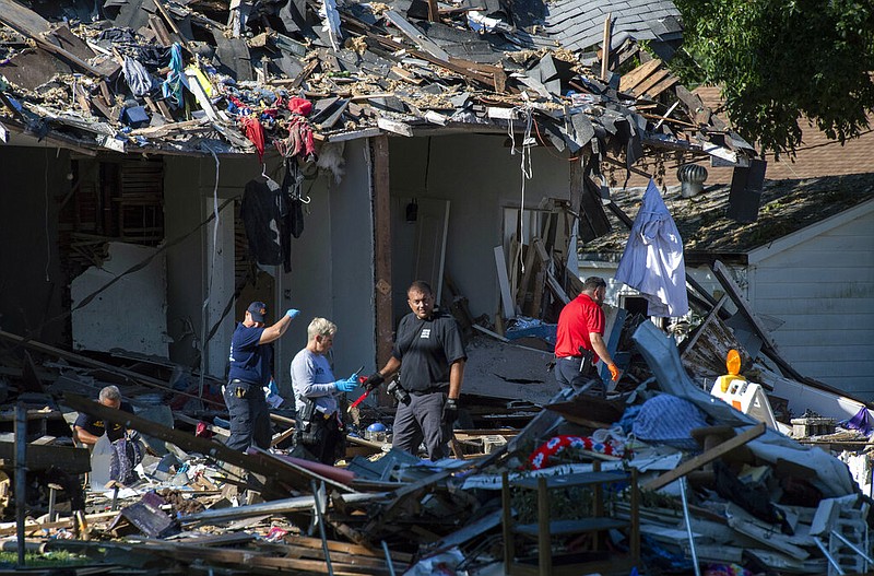 Emergency personnel search the debris in Evansville, Ind., on Thursday, Aug. 11, 2022, as authorities work to determine the cause of a house explosion that killed three people and left another person hospitalized. (MaCabe Brown/Evansville Courier & Press via AP)