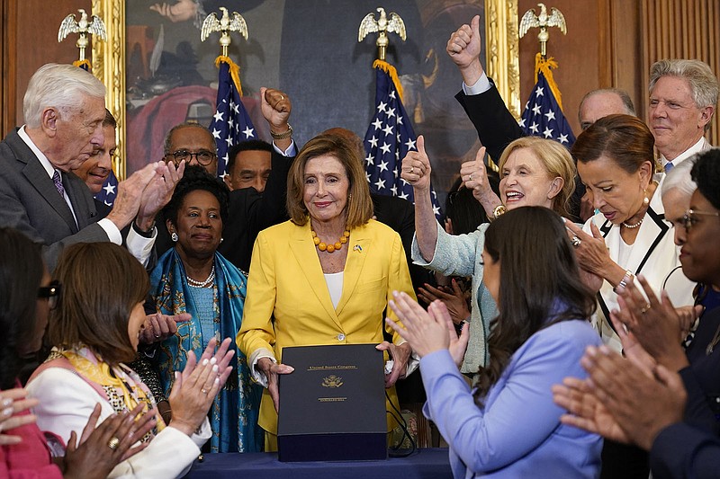 House Speaker Nancy Pelosi celebrates with fellow House Democrats on Friday during a bill enrollment ceremony on Capitol Hill. The legislation “meets the moment, ensuring that our families thrive and that our planet survives,” Pelosi said.
(AP/Susan Walsh)
