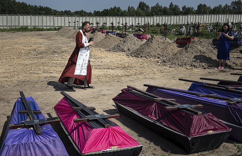 An Orthodox priest, Andrii, walks to bless coffins of unidentified civilians killed by Russian troops during the Russian occupation, on Wednesday in Bucha near Kyiv, Ukraine. Twenty-one unidentified bodies exhumed from a mass grave were buried in Bucha on Wednesday.
(AP/Evgeniy Maloletka)