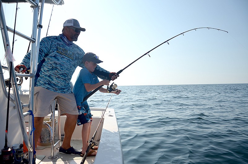 Photo contributed by Nick Carter / Captain Randy Cnota, who runs CNote Charters out of Panama City, Florida, steers the boat while also making sure young angler Nicholas Carter is not overwhelmed by a big bonito.