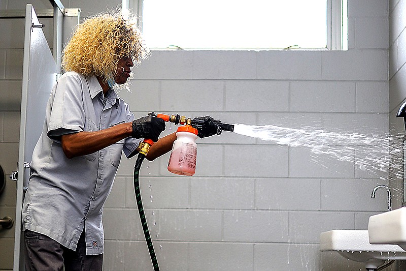 Staff photo by Olivia Ross  / Mae Washington sprays down the restroom with cleaning solution on April 29, 2022. She has worked as a custodian with Tennessee Riverpark for nearly 20 years. Washington's daily tasks include cleaning the restrooms, keeping the grounds litter free, and more.