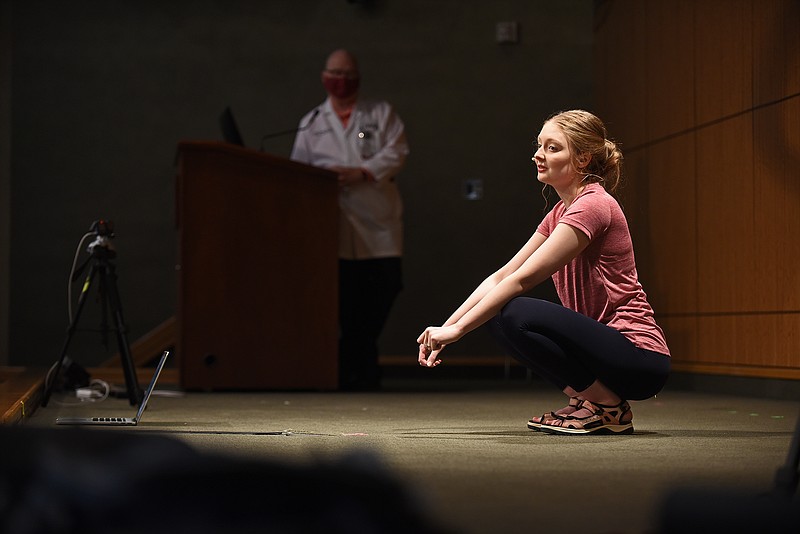 Gabby Rushing of North Little Rock answers questions from the audience while attempting to set the record for longest time to hold a deep squat Saturday at the University of Arkansas for Medical Sciences..(Arkansas Democrat-Gazette/Staci Vandagriff)