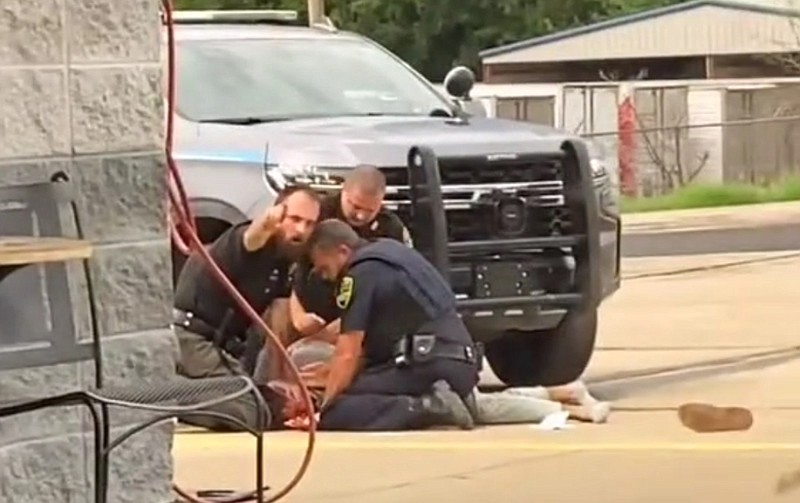 A law enforcement officer gestures toward a person recording the arrest of a man in Crawford County in this screenshot from a video recorded Sunday, Aug. 21, 2022. Crawford County Sheriff Jimmy Damante said the video shows two of his deputies and a Mulberry officer. (Courtesy Naomi Ruth Johnson, anthonyjohnson520; tiktok.com/@anthonyjohnson520/video/7134407649956777259)