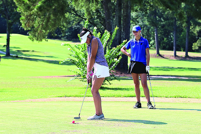 Junction City's Karla Castillo focuses on a putt as Parkers Chapel's Makenzie Morgan looks on. The two teams will join Cossatot in a tri-match on Wednesday at the Lions Club.