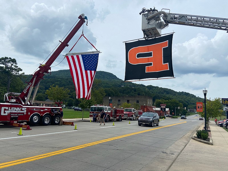 Staff Photo by Stephen Hargis / An American flag and a South Pittsburg High School flag hang above the highway on Aug. 24, 2022, as a procession of law enforcement vehicles, one was carrying the body of Marion County Sheriff’s Detective Matt Blansett to a local funeral home, moves through. Blansett and Tennessee Highway Patrol pilot Sgt. Lee Russell were killed Tuesday in a helicopter crash in east Marion County.