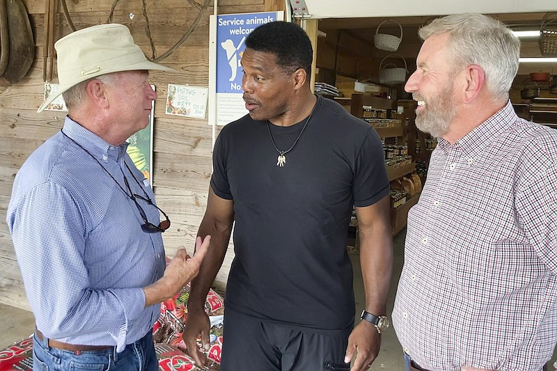 Republicans Senate candidate Herschel Walker, center, talks with Georgia state Sen. Butch Miller, left, and former state Rep. Terry Rogers as Walker campaigns July 21, 2022, in Alto, Ga. Walker has plenty to say about how his Democratic rival, Sen. Raphael Warnock, does his job in Washington. But he is considerably less revealing about what he'd do with the role himself. (AP Photo/Bill Barrow, File)