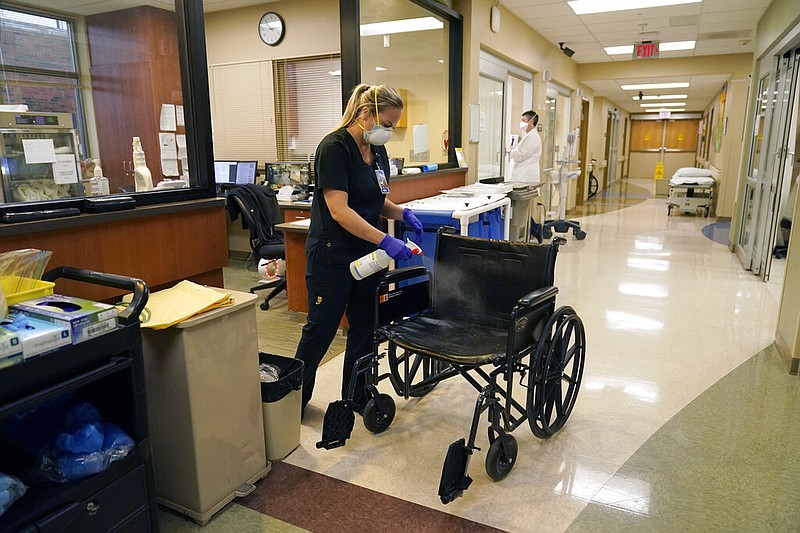 Registered nurse Chrissie Burkhiser disinfects a wheelchair in the emergency room at the 25-bed Scotland County Hospital in Memphis, Mo., in this Nov. 24, 2020 file photo. Scotland County Hospital serves rural northeast Missouri, particularly Memphis, which has fewer than 2,000 people. (AP/Jeff Roberson)