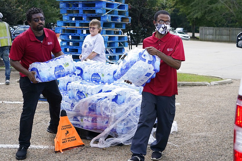 Salvation Army members carry cases of water to a waiting vehicle in Jackson, Miss., on Wednesday, Aug. 31, 2022. The organization and a local Walmart have established a mid-morning distribution site to assist residents in need of water. The recent flood worsened Jackson's longstanding water system problems, and the state Health Department has had Mississippi's capital city under a boil-water notice since late July. (AP/Rogelio V. Solis)