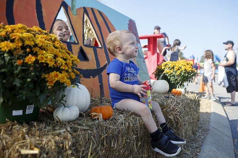 Staff photo by C.B. Schmelter / As his 4-year-old brother Charlie peaks through the eye of a pumpkin, 1-year-old Colton Silvers poses for a picture during a fall festival celebrating Ooltewah Nursery's 30th anniversary at Ooltewah Nursery and Landscape Company on Friday, Sept. 20, 2019 in Ooltewah, Tenn.