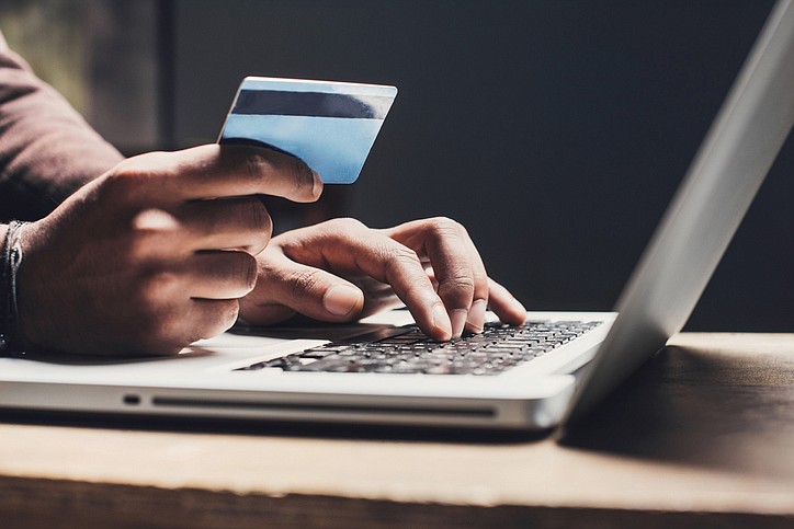 Men entering credit card information using laptop computer keyboard. Online shopping, computer fraud, scam concept. / Getty Images