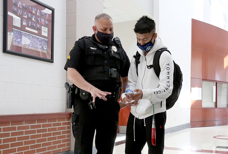 Cpl. John Scott, student resource officer at Springdale High School, visits with then-junior Marco Jarillo about the possible colors of lights for automobiles in the hallway of the school in this March 31, 2021 file photo. (NWA Democrat-Gazette/David Gottschalk)