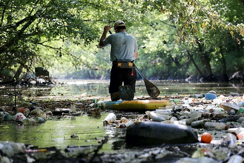 Staff Photo / Randy Whorton, director of Wild Trails, paddles through a section of Chattanooga Creek with a thick layer of trash covering the surface in 2018 in Chattanooga.