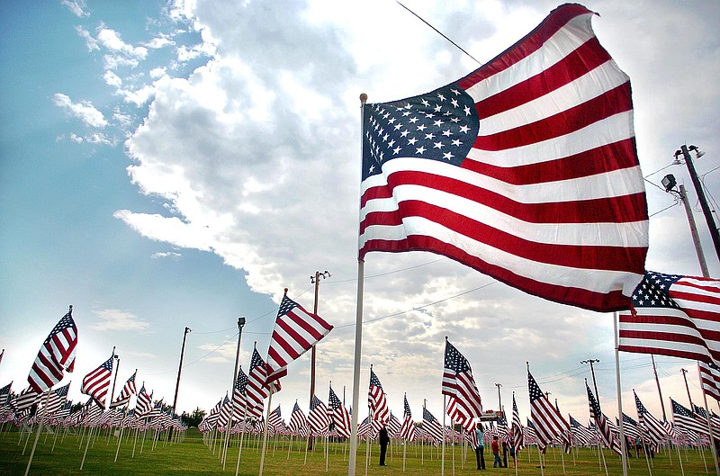 Brandon fireman Brad Brown and his family walk along a sea of American flags during a 9/11 remembrance ceremony held at the Crossgates Exchange Club soccer fields Sunday, Sept. 11, 2011, in Brandon, Miss. (AP Photo/The Clarion-Ledger, Vickie D. King)