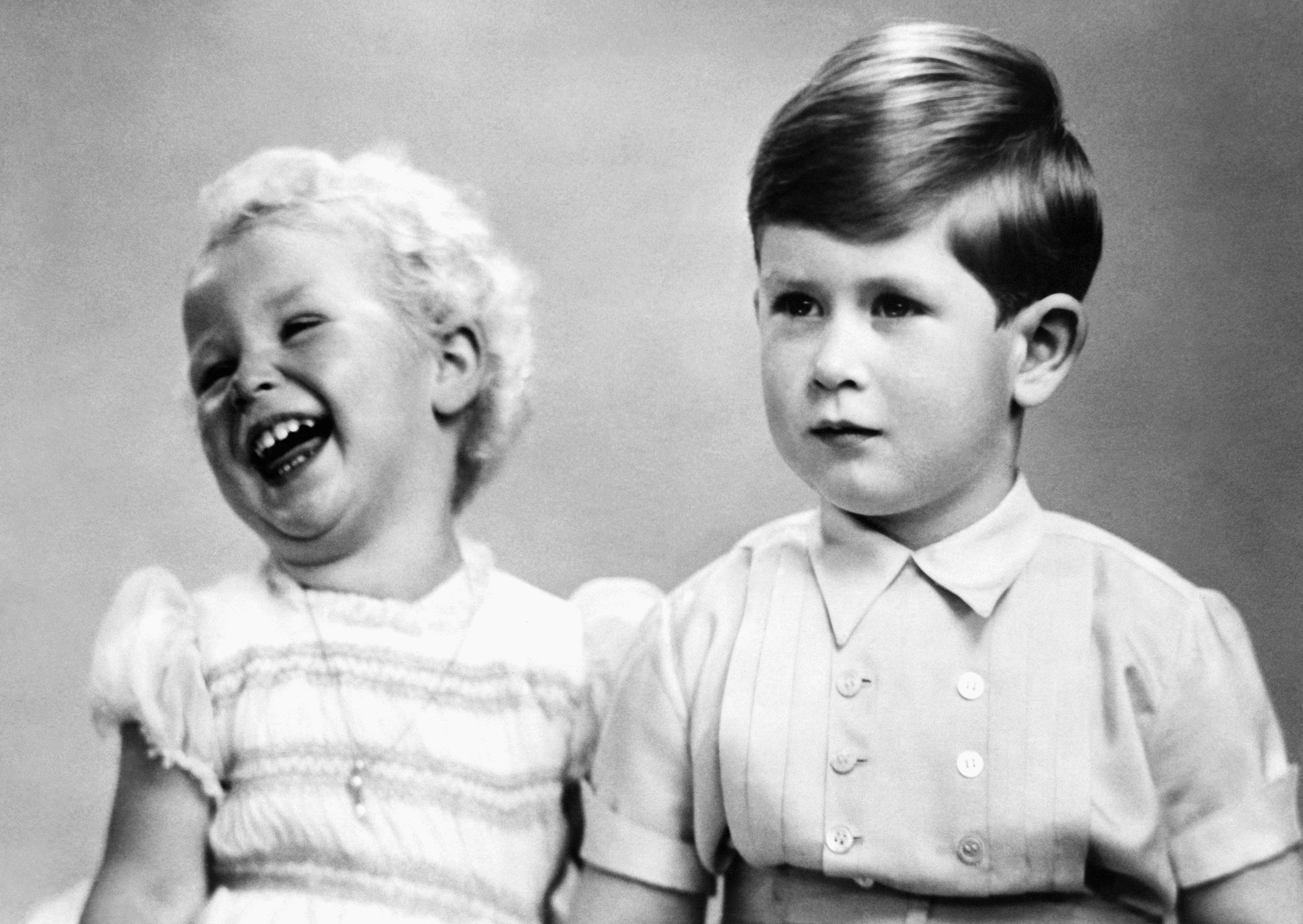 FILE - In this Nov. 14, 1952 file photo, Prince Charles, right, sits with his sister, Princess Anne, as they pose for a photo, at Balmoral Castle in Scotland. Prince Charles has been preparing for the crown his entire life. Now, that moment has finally arrived. Charles, the oldest person to ever assume the British throne, became king on Thursday Sept. 8, 2022, following the death of his mother, Queen Elizabeth II. (AP Photo/File)