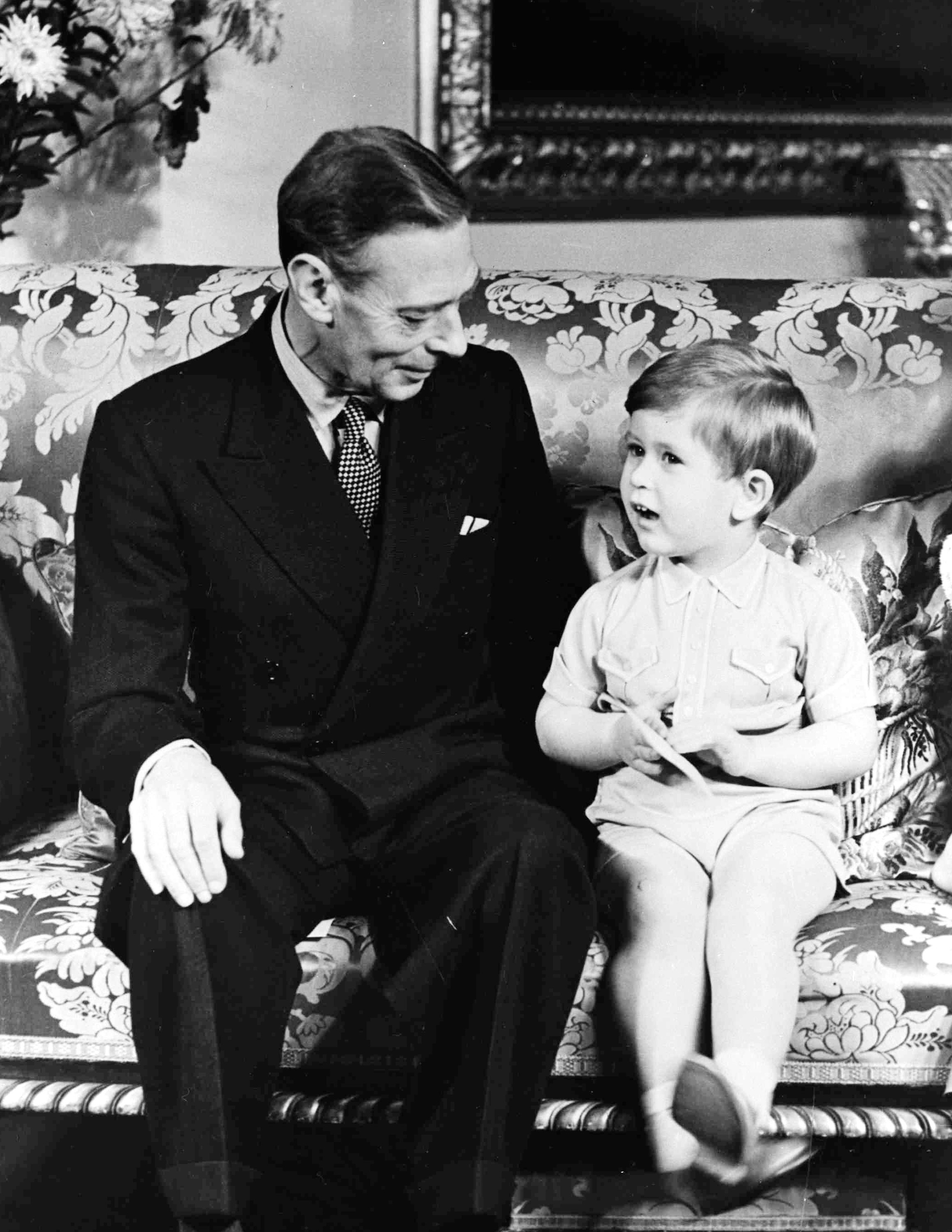 FILE - In this Nov. 14, 1951 file photo, Britain's King George VI sits with his grandson Prince Charles at Buckingham Palace, in London. The Prince was celebrating his third birthday. Prince Charles has been preparing for the crown his entire life. Now, that moment has finally arrived. Charles, the oldest person to ever assume the British throne, became king on Thursday Sept. 8, 2022, following the death of his mother, Queen Elizabeth II. (AP Photo/File)