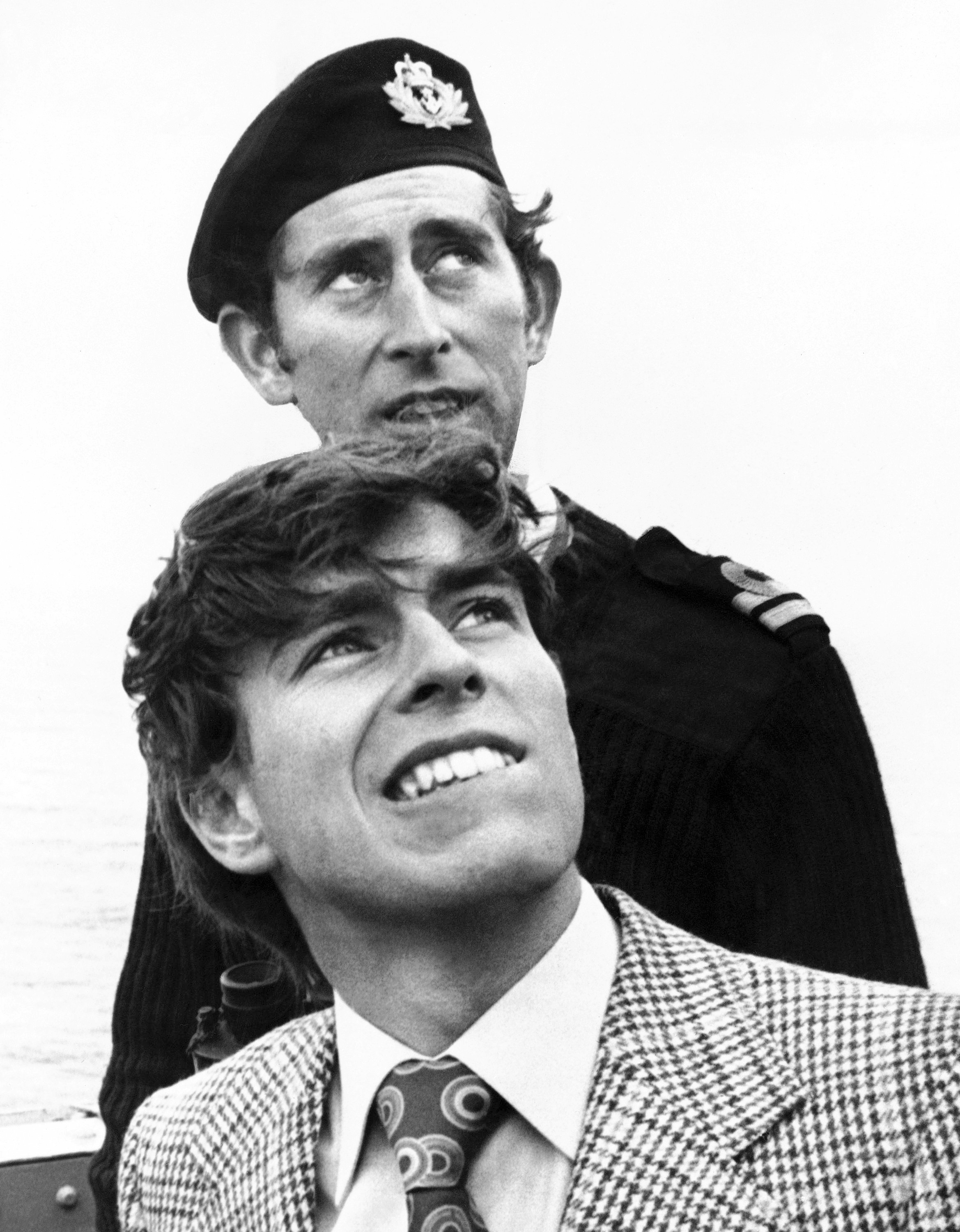 FILE - In this Dec. 15, 1076 file photo, Britain's Prince Andrew, foreground, with his elder brother, Prince Charles, look on during Prince Andrew's first visit on HMS Bronington. Prince Charles has been preparing for the crown his entire life. Now, that moment has finally arrived. Charles, the oldest person to ever assume the British throne, became king on Thursday Sept. 8, 2022, following the death of his mother, Queen Elizabeth II. (AP Photo, File)