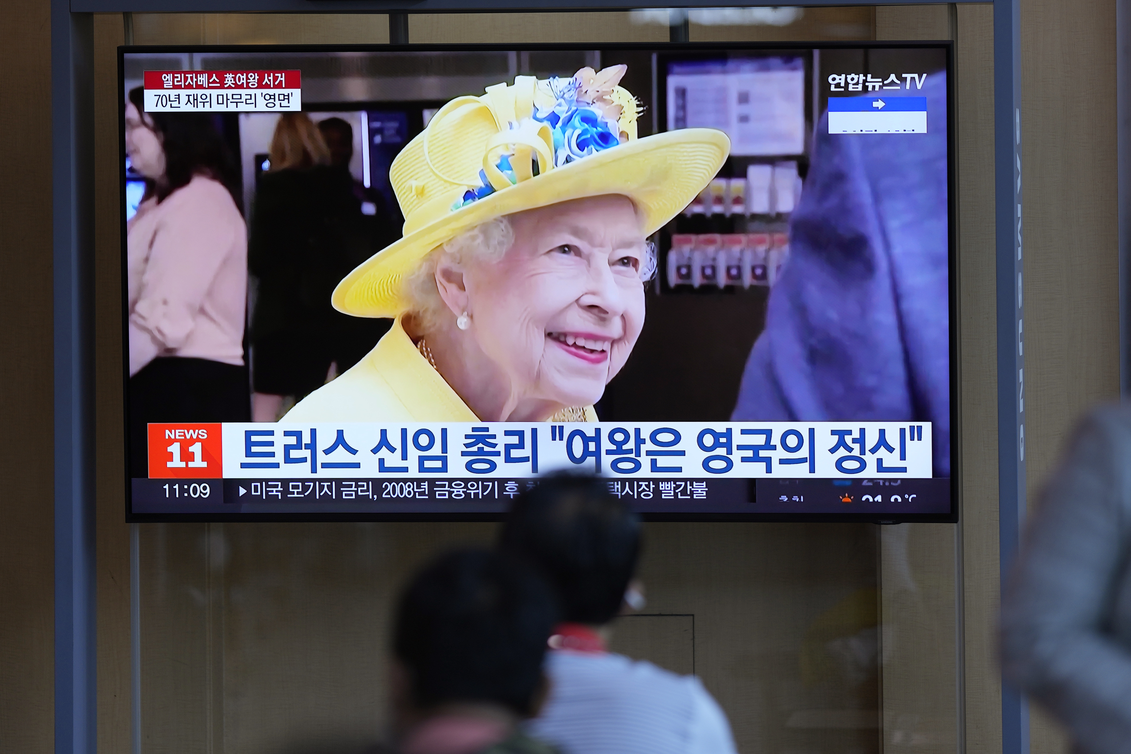 People watch a TV screen showing a news program reporting with a file footage of Queen Elizabeth II, at the Seoul Railway Station in Seoul, South Korea, Friday, Sept. 9, 2022. The letters read "British Prime Minister Liz Truss, "Queen was the very spirit of Great Britain." Condolences poured in from around the world Thursday after the death of Queen Elizabeth II, who became a global icon of calmness and fortitude through decades of political upheaval and social changes at home and abroad. (AP Photo/Lee Jin-man)