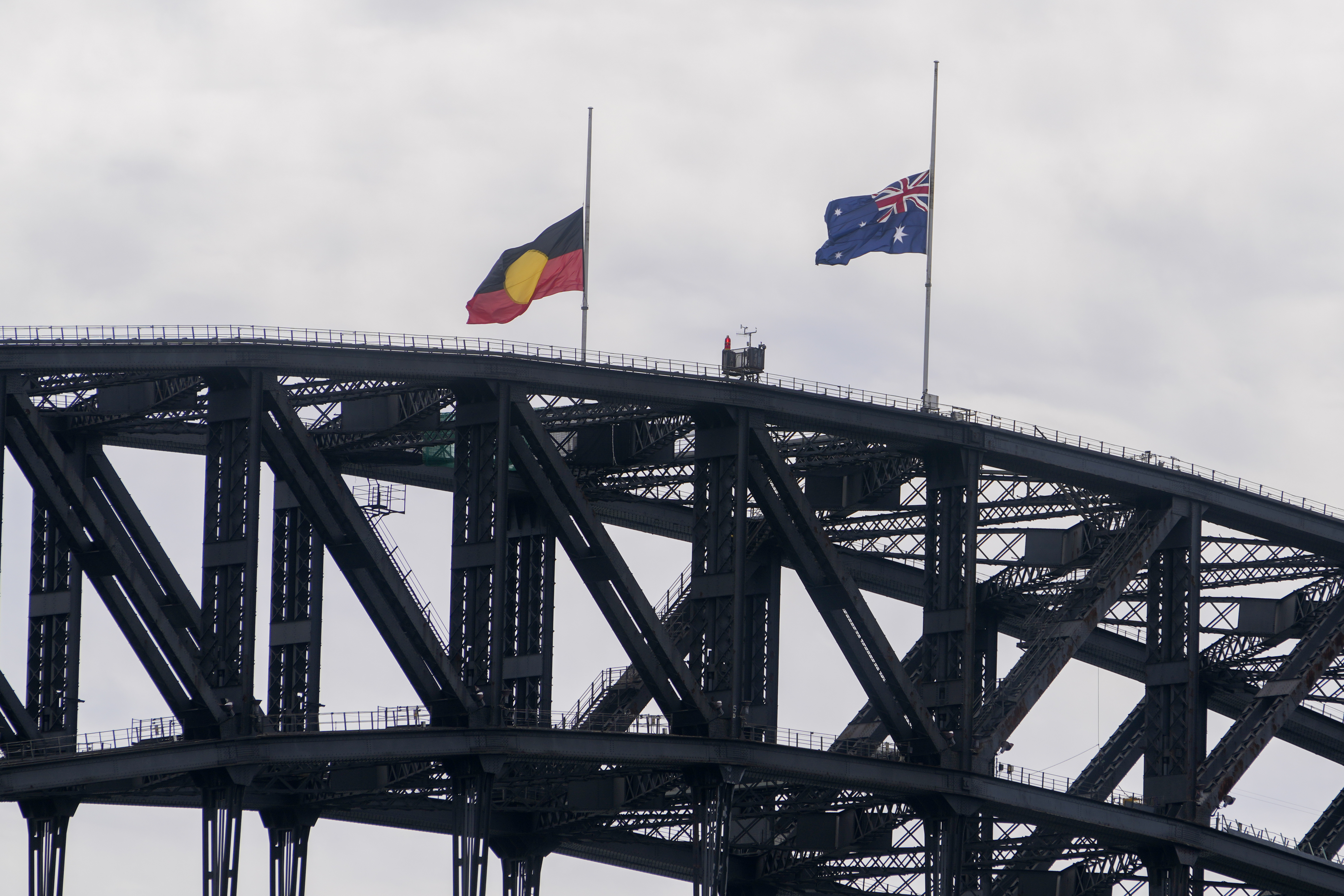 The Australian and Aboriginal flags fly at half mast atop of the Sydney Harbour Bridge following the passing of Queen Elizabeth II in Sydney, Australia, Friday, Sept. 9, 2022. Queen Elizabeth II, Britain's longest-reigning monarch and a symbol of stability in a turbulent era for her country and the world, died Thursday, Sept. 8 after 70 years on the throne. She was 96. ((AP Photo/Mark Baker)
