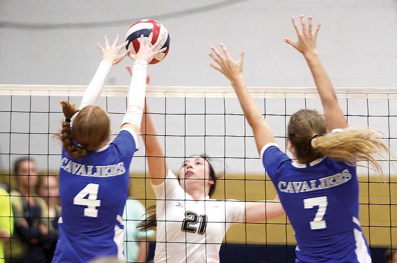 Faith Ann Meyer of Helias (center) reaches to hit the ball between Capital City’s Reagan Carel (left) and Ava Meinhardt (right) during Monday’s match at Helias Gym. (Greg Jackson/News Tribune)