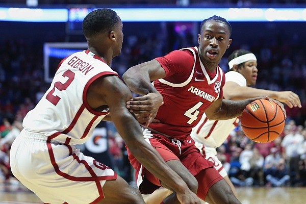 Arkansas guard Davonte Davis (4) drives past Oklahoma guard Umoja Gibson (2), Saturday, December 11, 2021 during the first half of a basketball game at the BOK Center in Tulsa.
