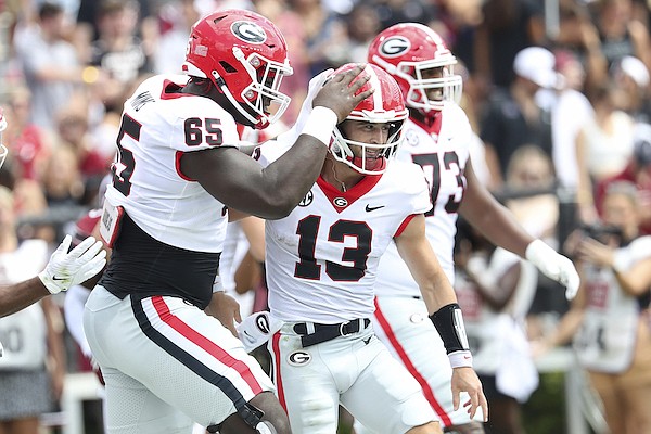 Georgia offensive lineman Amarius Mims (65) congratulates quarterback Stetson Bennett (13) during the first half of an NCAA college football game against South Carolina on Saturday, Sept. 17, 2022, in Columbia, S.C. (AP Photo/Artie Walker Jr.)