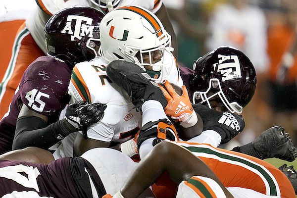Miami running back Thaddius Franklin Jr. (22) is stopped for a 1-yard loss by Texas A&M defenders, including linebacker Edgerrin Cooper (45), during the second half of an NCAA college football game Saturday, Sept. 17, 2022, in College Station, Texas. (AP Photo/Sam Craft)