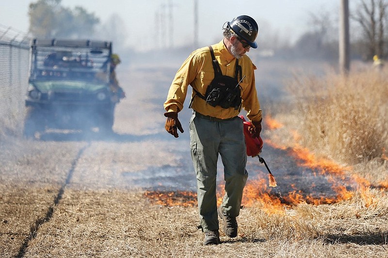 Brad Burns, the burn boss with Ozark Ecological Restoration Inc. of Siloam Springs, lights a perimeter line on the south end of Fayetteville's Woolsey Wet Prairie Sanctuary, a 62.5-acre wetland mitigation site, during a prescribed burn in this Feb. 24, 2021 file photo. The prescribed burn serves as a vegetation management effort. (NWA Democrat-Gazette/David Gottschalk)