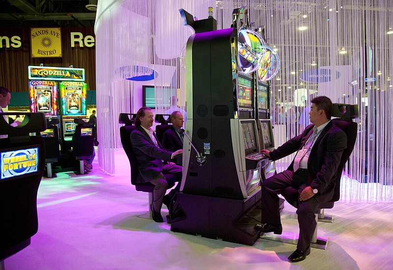 Casino industry representatives play on Wheel of Fortune slot machines at the International Game Technology exhibit during an industry conference in Las Vegas in this Oct. 4, 2011 file photo. (AP/Julie Jacobson)