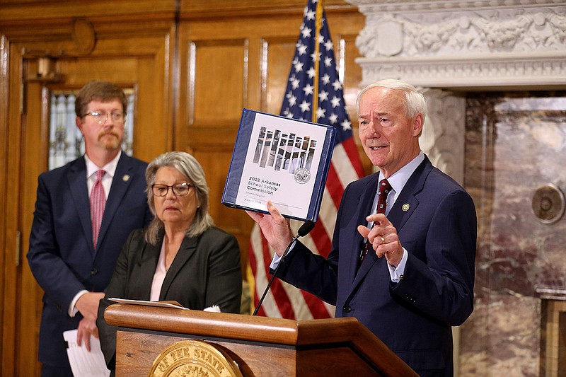 Gov. Asa Hutchinson holds a copy of the initial report from the Arkansas School Safety Commission during a press conference on Tuesday, Aug. 2, 2022, at the state Capitol in Little Rock. (Arkansas Democrat-Gazette/Thomas Metthe)