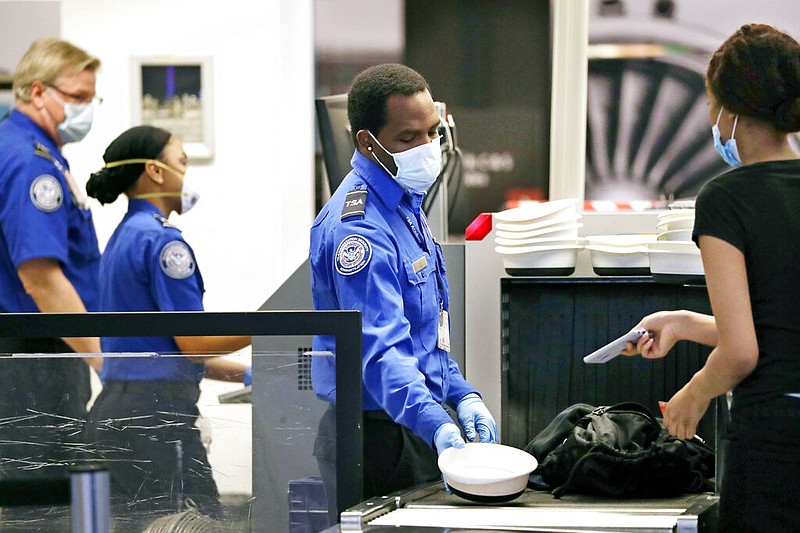 Transportation Security Administration officers process passengers at a security screening area at Seattle-Tacoma International Airport in SeaTac, Wash., in this May 18, 2020 file photo. (AP/Elaine Thompson)