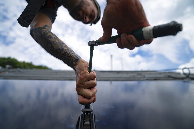 An employee of NY State Solar, a residential and commercial photovoltaic systems company, installs an array of solar panels on a roof in this Aug. 11, 2022 file photo. (AP/John Minchillo)