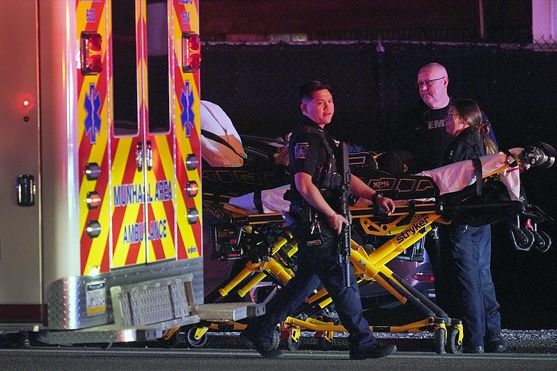 A law enforcement officer walks past an EMS crew on the scene at Kennywood Park, an amusement park in West Mifflin, Pa., early Sunday, Sept 25, 2022. Pennsylvania police and first responders have descended on the amusement park southeast of Pittsburgh following reports of shots fired inside the attraction, which was kicking off a Halloween-themed festival. (AP Photo/Gene J. Puskar)