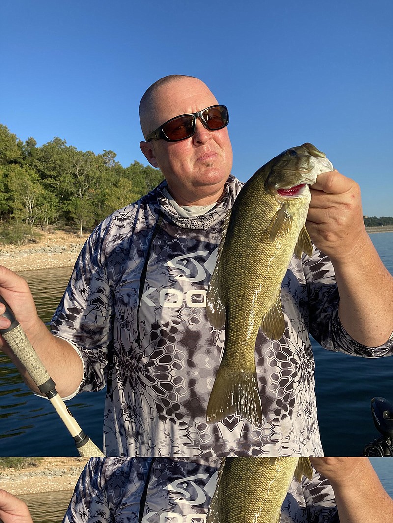 Mike Boyles examines a smallmouth bass caught Sept. 21 during an early evening trip on Table Rock Lake.
(Arkansas Democrat-Gazette/Bryan Hendricks)