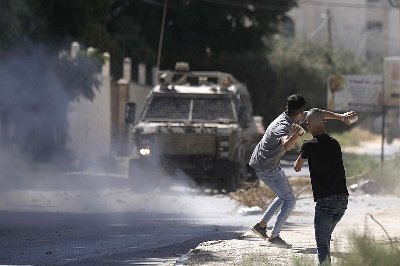 A Palestinian throws stones at an Israeli military vehicle Wednesday following a deadly raid in the occupied West Bank town of Jenin.
(AP/Majdi Mohammed)