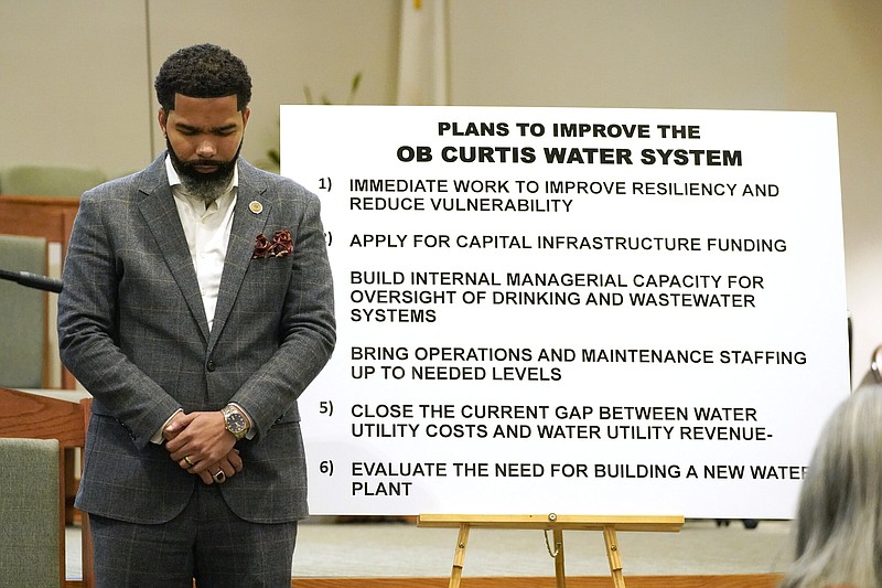 Mayor Chokwe Antar Lumumba stands in prayer near a poster outlined with plans for improving the primary water system plant at the start of a community meeting at College Hill Missionary Baptist Church, Jackson, Miss., on Sept. 13.
(AP/Rogelio V. Solis)