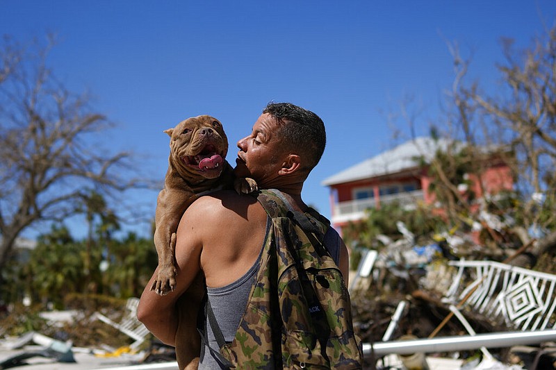 Eduardo Tocuya carries a dog he recovered in hopes of reuniting it with its owners, two days after the passage of Hurricane Ian, in Fort Myers Beach, Fla., Friday, Sept. 30, 2022. (AP/Rebecca Blackwell)