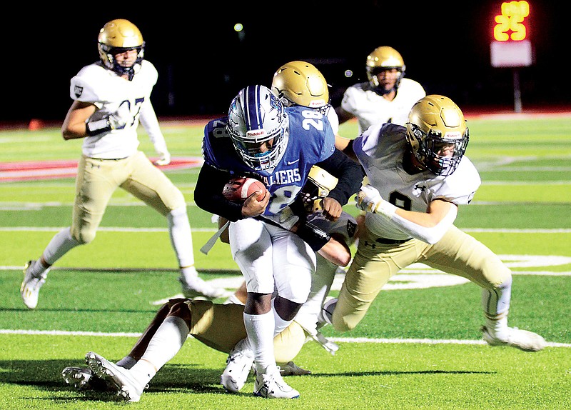 Three Helias defenders combine to bring down Jaylan Thomas of Capital City during Friday night’s game at Adkins Stadium. (Eileen Wisniowicz/News Tribune)