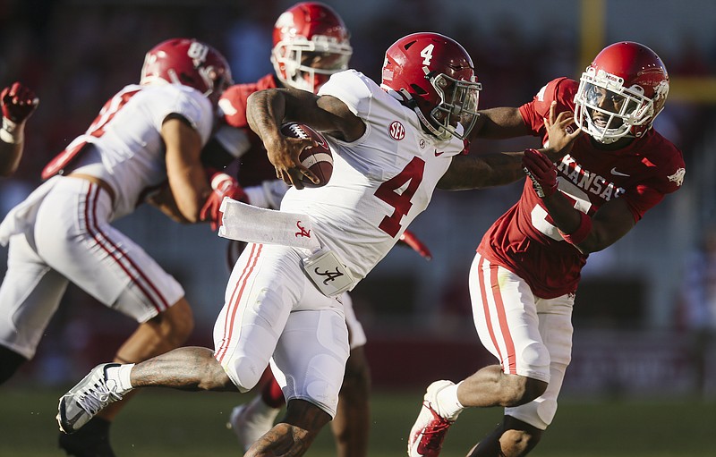 Alabama quarterback Jalen Milroe (4) carries the ball as he pushes off of Arkansas defensive back Dwight McGlothern (3), Saturday, October 1, 2022 during the third quarter of a football game at Donald W. Reynolds Razorback Stadium in Fayetteville. Visit nwaonline.com/221001Daily/ for today's photo gallery...(NWA Democrat-Gazette/Charlie Kaijo)