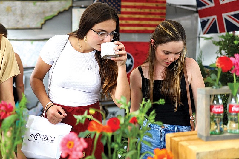 Staff photo by Olivia Ross  / Jamey Ryan and Jess Huff smell candles at the Kettle Creek Designs booth on August 21, 2022. Kettle Creek Designs, run by Christie Gobble, sells uniquely crafted candles, signs, and plants.