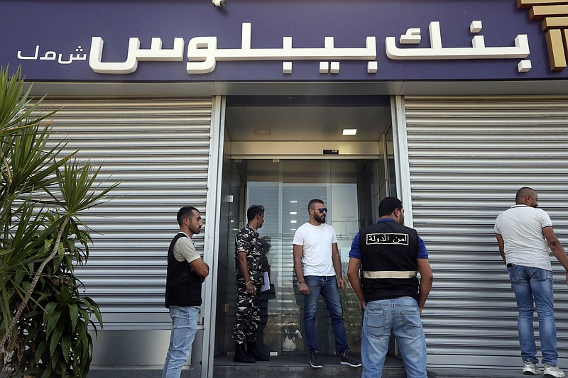 Lebanese security officers stand at the entrance of a Byblos Bank branch that was broken into by depositor Ali Hodroj holding a handgun, firing a warning shot and demanding about $40,000 of his trapped savings, in Tyre, south Lebanon, Tuesday, Oct. 4, 2022. Hodroj retrieved about $9,000 in Lebanese pounds following negotiations before he turned himself in to police outside the branch. Lebanese depositors, including a retired police officer, stormed at least four banks in the cash-strapped country Tuesday after banks ended a weeklong closure and partially reopened. (AP Photo/Mohammed Zaatari)