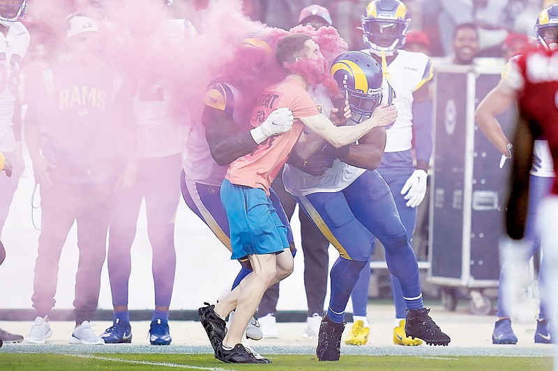 A fan running on the field is hit by Rams defensive end Takkarist McKinley (behind) and linebacker Bobby Wagner during Monday night's game against the 49ers in Santa Clara, Calif. (Associated Press)