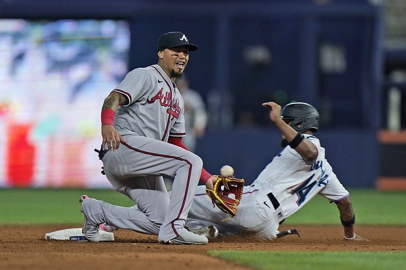Atlanta Braves second baseman Orlando Arcia is unable to hang on to a throw as Miami Marlins' Bryan De La Cruz (14) steals second base during the fifth inning of a baseball game, Wednesday, Oct. 5, 2022, in Miami. De La Cruz was safe at third on throwing error by catcher William Contreras. (AP Photo/Wilfredo Lee)