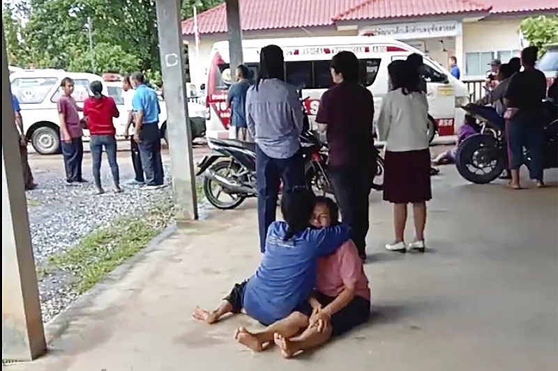 In this image taken from video, a distraught woman is comforted outside the site of an attack at a daycare center, Thursday, Oct. 6, 2022, in the town of Nongbua Lamphu, north eastern Thailand. More than 30 people, primarily children, were killed Thursday when a gunman opened fire in the childcare center authorities said. (Mungkorn Sriboonreung Rescue Group via AP)