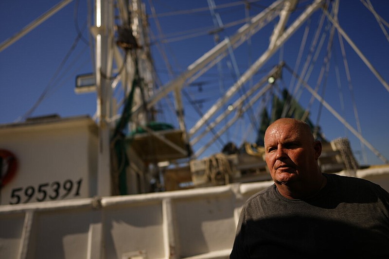 Jesse Clapham, shrimp boat fleet manager at Erickson & Jensen Seafood, walks in front of one of the boats he is hoping to get back out on the water quickly, after most of the fleet was grounded or damaged by the passage of Hurricane Ian, on San Carlos Island in Fort Myers Beach, Fla., Friday, Oct. 7, 2022. (AP Photo/Rebecca Blackwell)